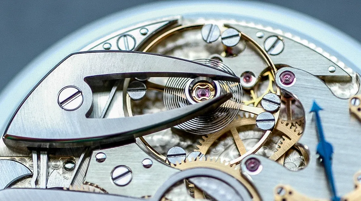 Крупный план сложного механического часового механизма, показывающего шестерни, пружины и крошечные камни.